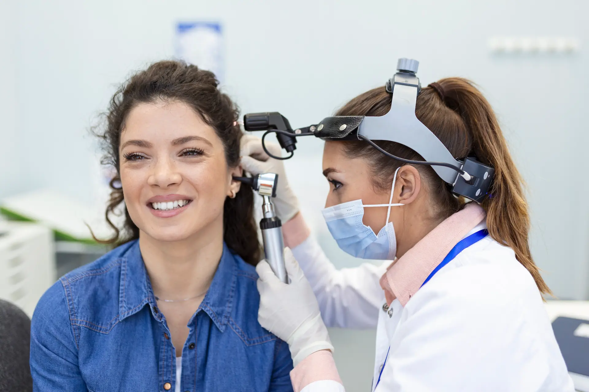 A pharmacist checks a patients ears with an otoscope before removing her earwax
